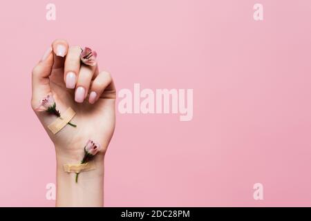 Pflaster mit Blumen auf weiblicher Hand isoliert auf rosa Stockfoto