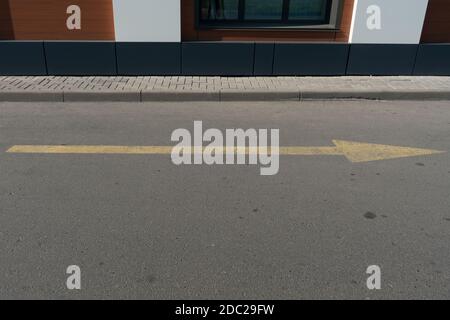 Gelber Pfeil auf dem Asphalt zeigt den Verkehr an. Stockfoto