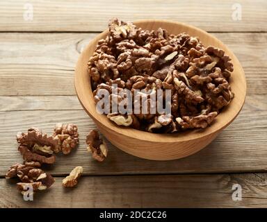 Geschälte Walnüsse in einer runden Holzschale stehen auf einem Holztisch, Draufsicht Stockfoto