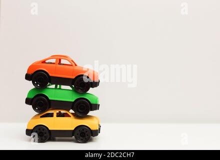 Drei bunte Spielzeugautos aus recycelbarem ungiftigem Kunststoff auf weißem Hintergrund mit Schatten, Null Abfall, Energiesparen Konzept Stockfoto