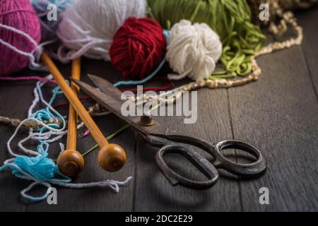 Variation of wool balls for knitting with old scissors in vintage style on wooden background Stockfoto