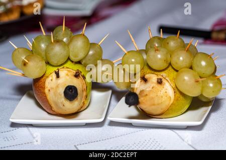 Früchtedessert. Igel aus Birnen und Trauben Stockfoto