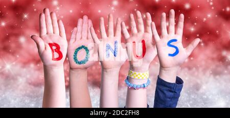 Kinder Hände Gebäude Bunte Englisch Wort Bonus. Red Snowy Weihnachten Winter Hintergrund Mit Schneeflocken Und Funkelnden Lichtern Stockfoto