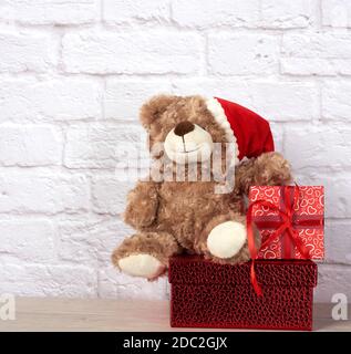 teddybär in weihnachtsmann Hut und Box mit rotem Band gebunden, weihnachtshintergrund Stockfoto