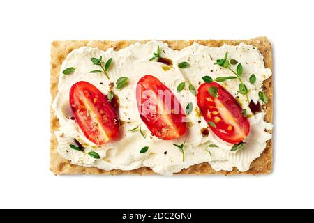 Brotchips mit Frischkäse, Tomatenscheiben und Kräutern auf Weiß Stockfoto