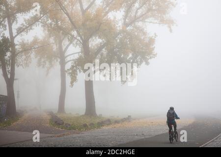 Radfahrer am Rheinufer im Landkreis Deutz, nebliger Herbsttag, Köln, Deutschland. Radfahrer an der Deutzer Werft, nebeliger Herbsttag, Koe Stockfoto