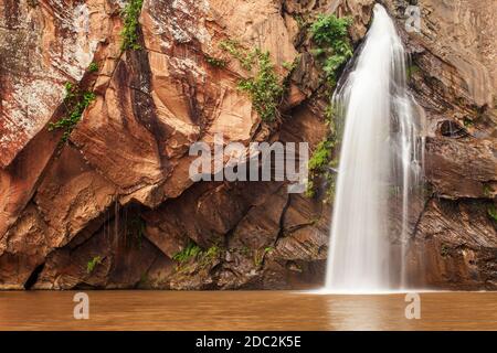 Wunderschöner Wasserfall an einer großen Sandsteinwand in der Regenzeit, abstrakte Struktur einer alten Sandsteinmauer. Namtok Chat Trakan Nationalpark, Thailand. Stockfoto