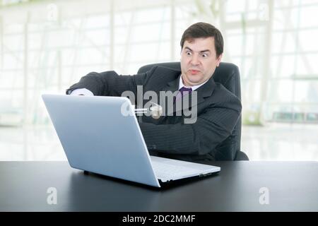 verrückte Geschäftsmann mit einem Hammer zertrümmern einen Laptop im Büro Stockfoto