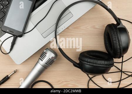 Laptop, Mikrofon, Kopfhörer liegt auf einem Holztisch, Hintergrund, Draufsicht Stockfoto