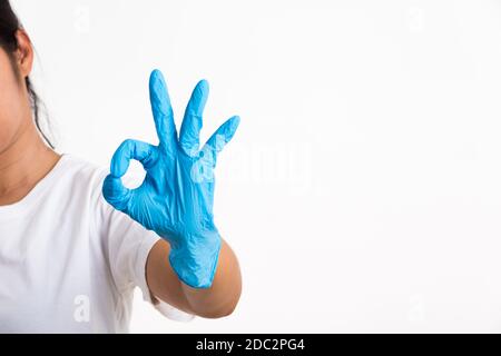 Frau trägt und Putting Hand zu blauen Latex-Handschuh für Arzt mit OK-Zeichen gestikulieren, Studio-Aufnahme isoliert auf weißem Hintergrund, Krankenhaus Medica Stockfoto