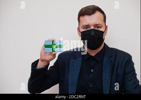 Mann tragen schwarz formell und schützen Gesichtsmaske, halten Derbyshire Flagge Karte isoliert auf weißem Hintergrund. Vereinigtes Königreich Grafschaften von England Coronavirus Co Stockfoto