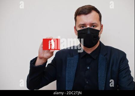 Mann tragen schwarz formell und schützen Gesichtsmaske, halten Warwickshire Flagge Karte isoliert auf weißem Hintergrund. Vereinigtes Königreich Grafschaften England Coronavirus Stockfoto