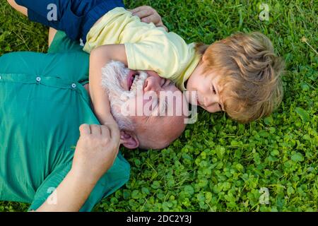 Umarmung auf grünem Gras - Großvater und Enkel. Großvater mit Sohn und Enkel Spaß im Park. Generation der Männer. Stockfoto