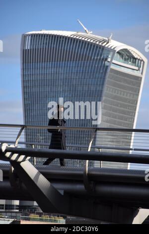 Ein Mann mit einer schützenden Gesichtsmaske geht auf der Millennium Bridge mit der Fenchurch Street 20 - aka Walkie Talkie Building - im Hintergrund, als die zweite nationale Sperre in England greift. Stockfoto