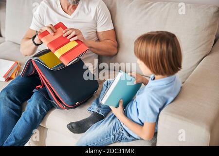 Kleine Familie von Vater und Kind Auspacken einer Schultasche Stockfoto