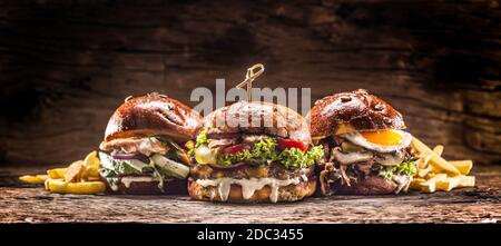 Vorderansicht auf drei große, Rindfleisch Lachs und Kebab Burger gefüllt mit frischem Gemüsesalat und Dressing Stockfoto
