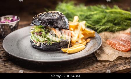 Schwarzer Burger gefüllte Lachs Avocado und Gurkensalat mit Pommes frites Stockfoto