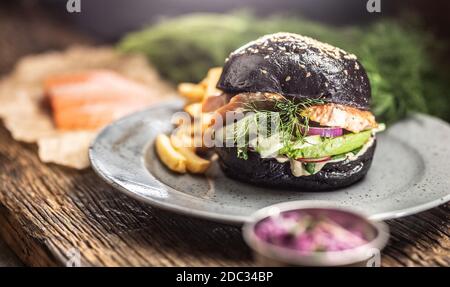 Schwarzer Burger gefüllte Lachs Avocado und Gurkensalat mit Pommes frites Stockfoto