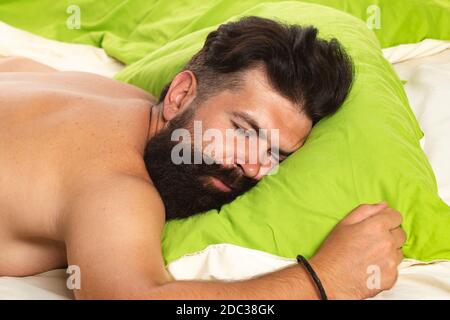 Mann schläft auf dem Bett mit sehr tiefen Schlaf. Junger Mann schläft auf dem Bett. Junger Mann im Bett - versucht zu schlafen. Stockfoto