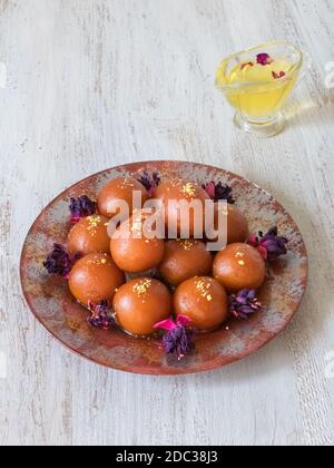 Gulab Jamun: Traditionelle indische Süßigkeiten auf einem weißen Holztisch. Stockfoto