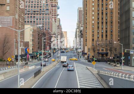 1st Avenue in Manhattan. Autos und gelbe Taxis auf der Straße. Moderne Gebäude und Wolkenkratzer entlang der Long Road. New York, USA Stockfoto