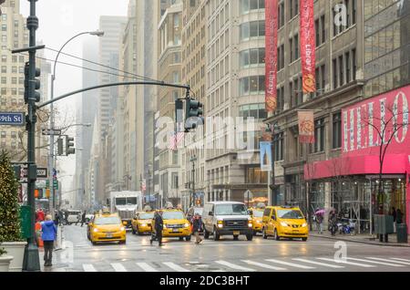 Gelbe Taxis und andere Fahrzeuge warten auf die Fußgänger, um die Straße in Manhattan zu überqueren. Weihnachten an einem Foggy Tag. New York City, USA Stockfoto