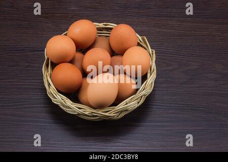 Eier Hähnchen im Korb auf braunem dunklen Holzboden. Stockfoto