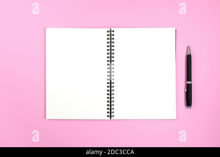 Leere Seiten mit offenem Spiralnotepad und Bleistift auf rosa Hintergrund Stockfoto