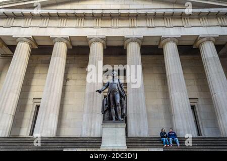 Ehepaar sitzt vor dem Federal Building in der Wall Street. Gebäude im griechischen Stil im Finanzviertel, Manhattan, New York City, USA Stockfoto