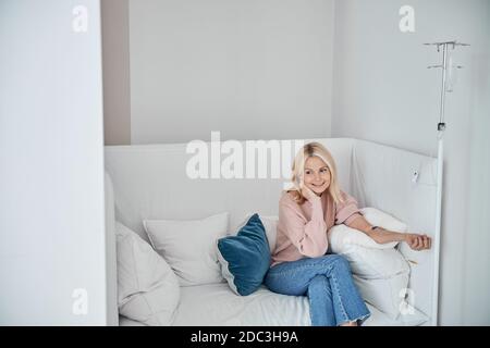 Erfreut hübsche Dame lächelnd während der intravenösen Vitaminbehandlung Stockfoto
