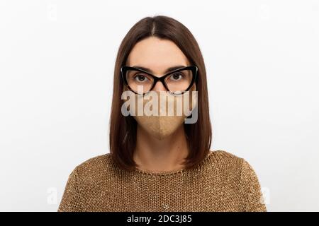 Headshot Porträt der schönen tausendjährigen Frau in einem schützenden medizinischen Maske in Brille und Pullover stehen isoliert auf grauen Studio Hintergrund Stockfoto