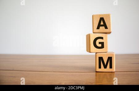 Holzwürfel mit Akronym "AGM" - "Jahreshauptversammlung" auf einem schönen Holztisch, weißer Hintergrund. Geschäftskonzept, Kopierbereich. Stockfoto