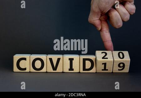 Hand dreht Würfel und ändert das Wort 'covid19' in 'covid20'. Schöner grauer Hintergrund. Konzept. Speicherplatz kopieren. Stockfoto