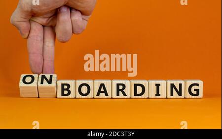 Hand dreht Würfel und ändert den Ausdruck 'Boarding' in 'Onboarding'. Schöner orangefarbener Hintergrund. Geschäftskonzept. Speicherplatz kopieren. Stockfoto