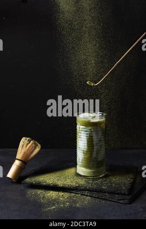 Japanischer Matcha Latte und Matcha Werkzeuge auf schwarzem Hintergrund. Erfrischung Eis Matcha Tee mit Milch. Stockfoto