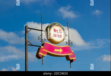 Straßenschild mit Text "jetzt, es ist Ihre Umdrehung" und Pfeil-Zeichen auf Metallstange. Blauer Himmel Hintergrund. Wohltätigkeitsorganisation. Geschäftskonzept, Kopierbereich. Stockfoto