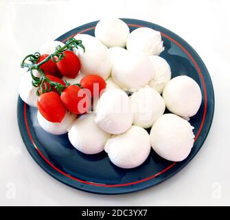 Mozzarella in einem schönen blauen Teller mit roten Kirschtomaten Isoliert auf weißem Hintergrund Stockfoto