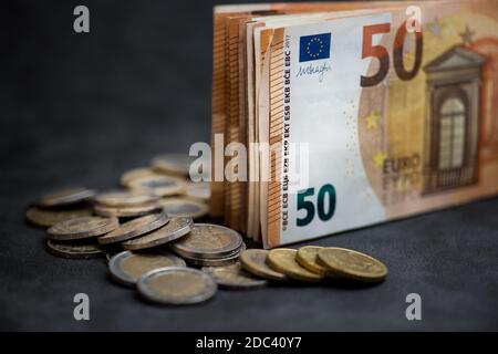 Ein Stapel von 50 Euro Geld und viele Euro-Münzen Auf einem dunklen Hintergrund Stockfoto