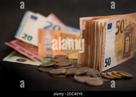 Ein Stapel von 50 Euro Geld und viele Euro-Münzen Auf einem dunklen Hintergrund Stockfoto