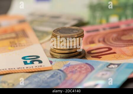 Euro-Banknoten und gestapelte Münzen auf einem farbigen Hintergrund Stockfoto