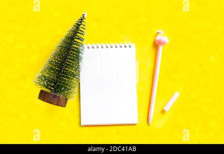 Arbeitsbereich. Weihnachtsbrief. Spiralnotizblock und pinker Stift auf gelbem Hintergrund. Draufsicht mit Kopierplatz, flach liegend Stockfoto