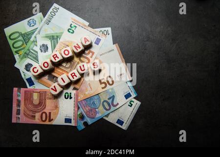 euro-Banknoten auf dunklem Hintergrund mit Coronavirus-Inschrift Ansicht Von oben Stockfoto