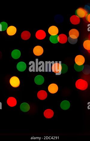 Bunte Bokeh aus Girlanden auf schwarzem Hintergrund. Eine vielseitige festliche und magische Kulisse. Weihnachten, Neujahr, halloween. Rot, gelb, grün, Stockfoto