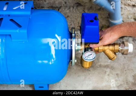 Installation einer Wasserversorgungsstation zu einem Wohngebäude mit einem Hydraulikspeicher. Pumpstation. Stockfoto