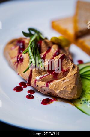 Foie Gras Mousse aus Entenleber zum Abendessen Restaurant.Gourmet Gänsefleisch Rilletten mit Rosmarin Kräuter & Cranberry serviert Sirup auf weißem Cera Stockfoto