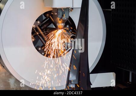 Laserschneidmaschine arbeitet mit zylindrischem Metallwerkstück mit Funken Stockfoto