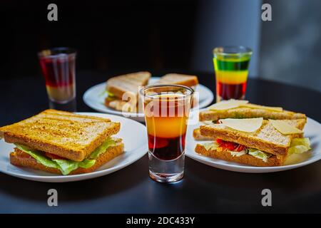 Club Sandwiches und mexikanische Gerichte werden zur Party in der Bar serviert Essen und starke alkoholische Getränke auf dem Tisch im Nachtclub Stockfoto