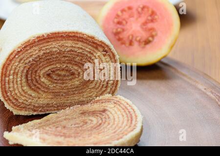 Brötchen Kuchen (bolo de rolo) Nahaufnahme auf einem Holzbrett neben einer Guave. Stockfoto