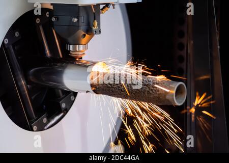 Laserschneidmaschine arbeitet mit zylindrischem Metallwerkstück mit Funken Stockfoto