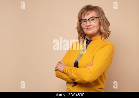 Lächelnde reife Geschäftsfrau in Brille mit gefalteten Händen Stockfoto
